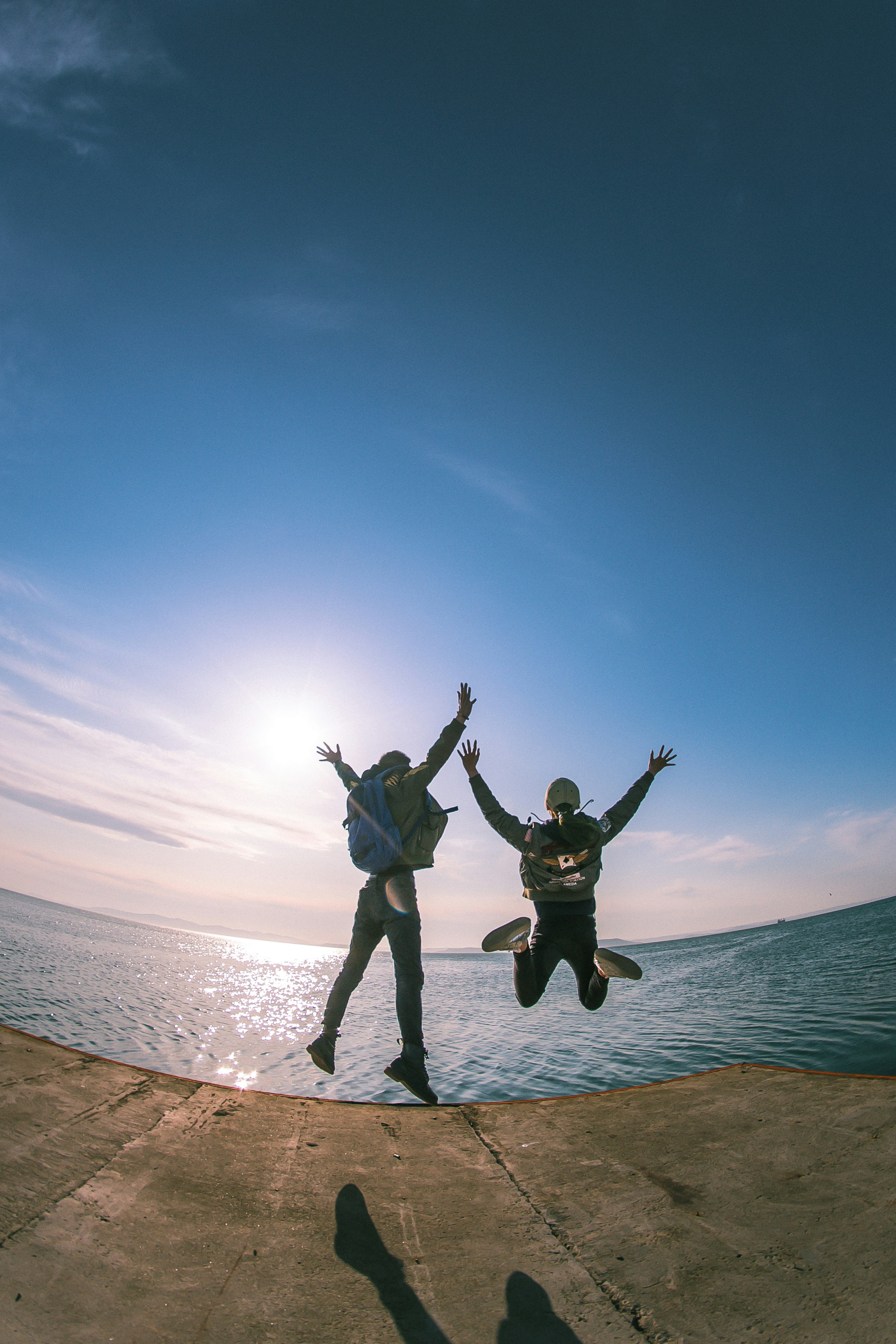 2 men jumping on beach during daytime